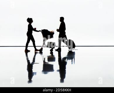 Silhouette von Mann und Frau mit Gepäck auf einem Flughafen Stockfoto