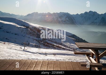 Saint-François-Longchamp : Höhe sonnigen Tag mit einem Holztisch und Boden auf der rechten Seite und Sessellift im Hintergrund. Maurienne Savoie Stockfoto