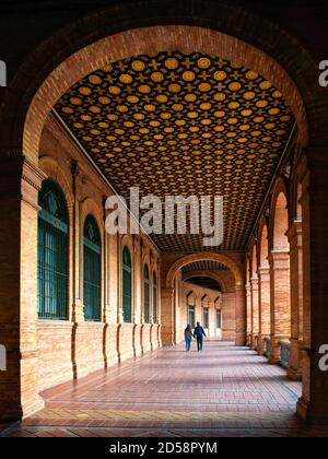 Rückansicht von zwei Personen, die durch die Plaza de Espana, Maria Luisa Park, Sevilla, Spanien gehen Stockfoto