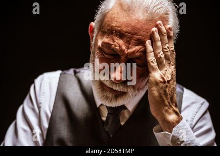 Porträt des depressiven Seniors auf schwarzem Hintergrund. Stockfoto