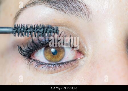 Nahaufnahme des Auges einer jungen Frau beim Anziehen Make-up mit Mascara für ihre Wimpern Stockfoto