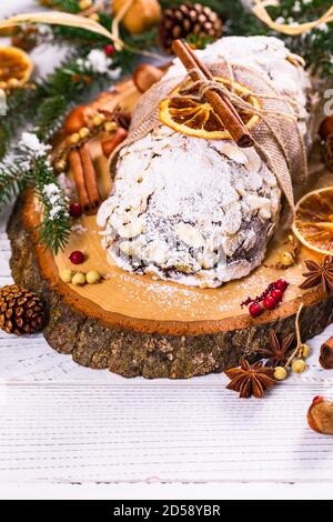 Deutscher Stollen Weihnachtskuchen auf einem rustikalen Schneidebrett mit Weihnachtsschmuck Stockfoto