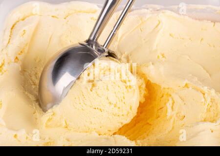 Nahaufnahme von Vanilleeis, das von einer mechanischen Schaufel aufgeballert wird. Stockfoto
