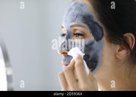 Junge Frau wäscht weg schwarzen Ton Maske aus Gesicht Porträt Stockfoto