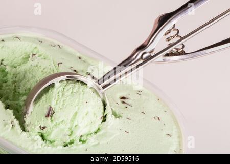 Nahaufnahme von Minzchip-Eis, das von einem mechanischen Messlöffel aufgeschöpft wird, um serviert zu werden. Stockfoto