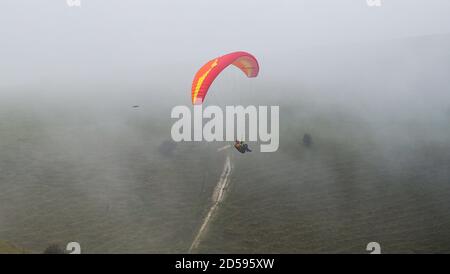 Brighton UK 13. Oktober 2020 - Gleitschirme steigen über den Morgen Herbstnebel über Devils Dike nördlich von Brighton, da trockeneres, eher sesshaftes Wetter für später in der Woche in ganz Großbritannien prognostiziert wird : Credit Simon Dack / Alamy Live News Stockfoto