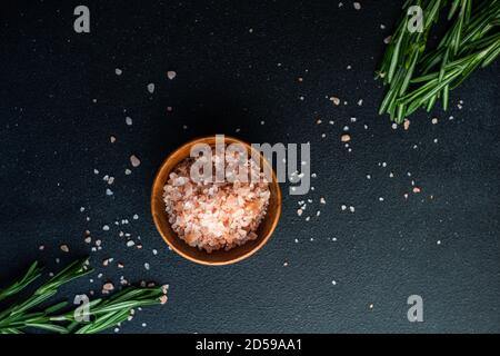 Ansicht von oben auf eine Schüssel mit rosa Himalaya-Steinsalz Und frischen Rosmarin Stockfoto