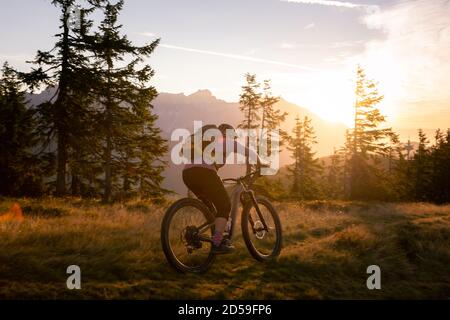 Frau Mountainbiken in den Bergen bei Sonnenaufgang, Fadstadt, Salzburg, Österreich Stockfoto