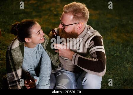 Freunde, die Spaß am Abend Picknick mit Getränken. Junge kaukasische Paar beim bbq auf dem Land Stockfoto