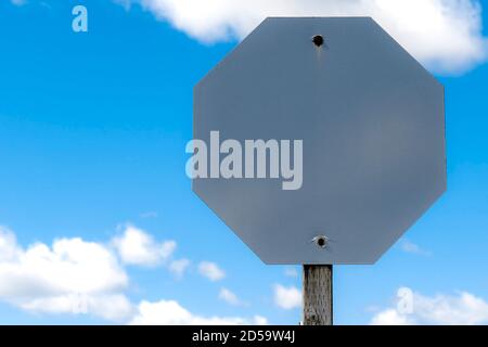 Ein leeres Stoppschild. Die Färbung hat sich vollständig abgenutzt, so dass nur das leere Metallschild. Auf der Oberfläche befindet sich ein feines Hexadezimalmuster. Blauer Himmel mit einigen c Stockfoto