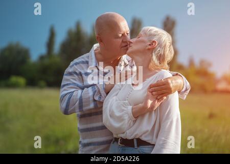 Glückliches Seniorenpaar Dating, Umarmung und küssen im Freien bei Sonnenuntergang Stockfoto