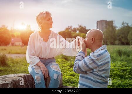 Älterer Mann hält und küsst Frau Hand auf Datum in parken Stockfoto