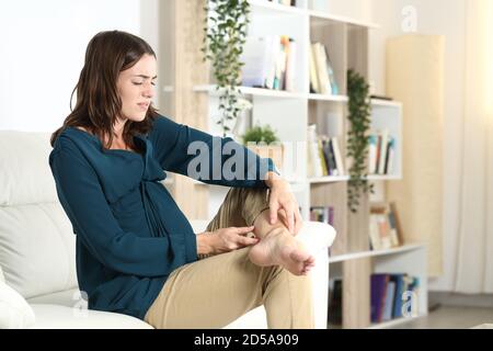 Schwangere Frau mit Knöchelschmerzen, die sich auf einem Sofa beschwert Im Wohnzimmer zu Hause Stockfoto