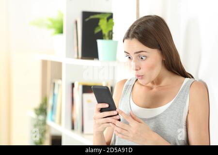 Überrascht Frau prüft Handy-Inhalte zu Hause stehen Stockfoto