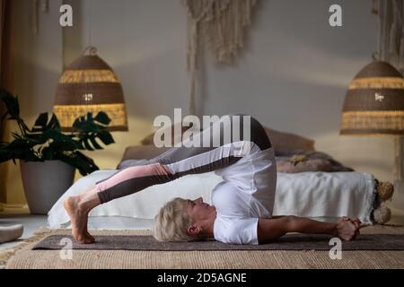 Ältere Frau praktiziert Yoga, Stretching in Pflug Übung, Halasana Pose, trainieren Stockfoto