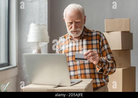 Älterer Mann, der online mit Kreditkarte und Laptop kauft Stockfoto