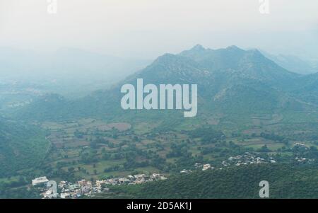 Blick vom Monsoon Palace über die ländliche Landschaft in Richtung Gipfel der Aravalli Hügel bei Sonnenaufgang am nebligen Morgen in Udaipur, Rajasthan, Indien. Stockfoto