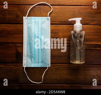 Medizinische Gesichtsmaske mit Alkohol Desinfektionsmittel Gel Handwäsche auf Holztisch für covid-19 Stockfoto