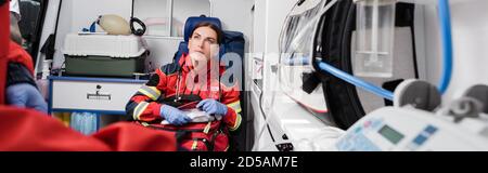 Panoramaaufnahme eines Sanitäters mit einem Verbandskasten in der Nähe Kollege im Ambulanzwagen Stockfoto