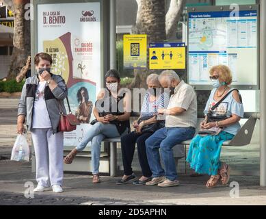 Las Palmas, Gran Canaria, Kanarische Inseln, Spanien. Oktober 2020. Menschen mit Gesichtsbezügen warten in Las Palmas auf Gran Canaria auf einen Bus. Die Wirtschaft der Kanarischen Inseln leidet unter dem Mangel an Touristen aus dem Vereinigten Königreich. Obwohl sie eine der Provinzen Spaniens mit den geringsten Covid-Fällen sind, bleiben die Kanarischen Inseln wie auch der Rest Spaniens auf der Quarantäneliste des Vereinigten Königreichs. Kredit: Alan Dawson/Alamy Live Nachrichten. Stockfoto