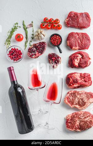 Rohes Set von alternativen Beef Cuts Chuck Augenrolle, obere Klinge, Rumpsteak mit Rotwein in Glas und Flasche, Kräuter und Granatapfel. Bio-Fleisch. Weiß Stockfoto