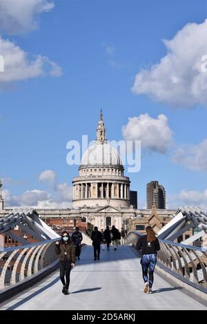 Eine Frau mit einer schützenden Gesichtsmaske geht über die Millennium Bridge mit der St. Paul's Cathedral im Hintergrund. London, Großbritannien 2020. Stockfoto