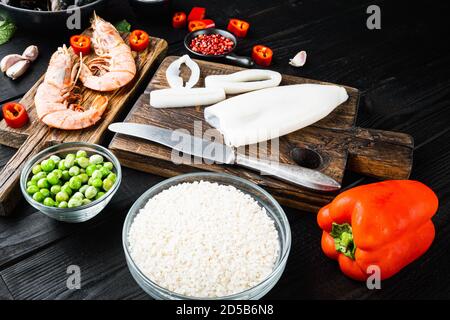 Meeresfrüchte für traditionelle spanische Paella-Spezialitäten auf schwarzem Holzhintergrund Stockfoto