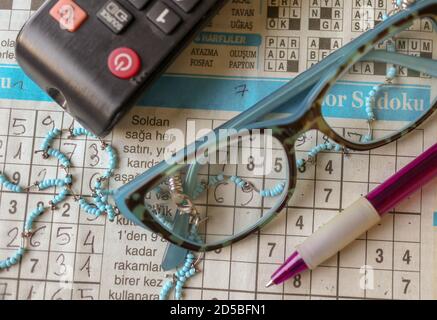 Stift, Brille, TV-Controller, Zeitung, Sudoku, moderne Ruhestandszeit Stockfoto