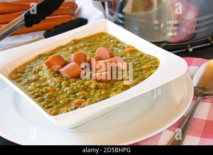 Herzhafte Erbsensuppe mit Hot Dogs in einem weißen serviert Schüssel auf einem Tisch - Nahaufnahme Stockfoto