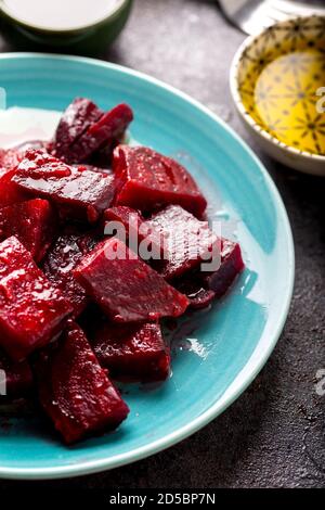 Rote Beete Salat mit Knoblauch und Olivenöl-Sauce in Schale auf dunklem Hintergrund. Stockfoto