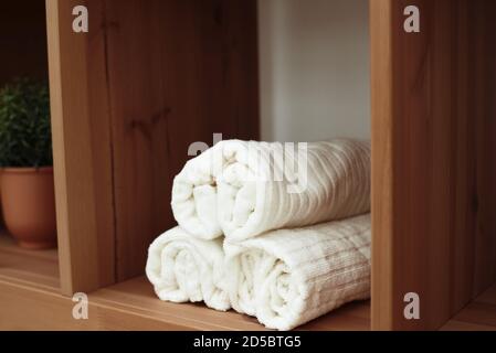 Weiße, weiche Handtücher auf dem Regal im Badezimmer. Stockfoto