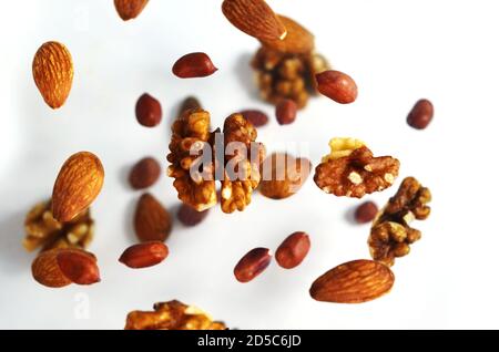 Nüsse in der Luft auf weißem Hintergrund, fliegende Nüsse. Gesunde Ernährung Gehirn, Ernährung, Protein, Mandeln, Walnüsse und Haselnüsse Erdnuss Stockfoto