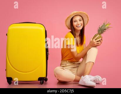 Entzückte Dame in Sommerkleidung mit Ananas auf rosa Stockfoto