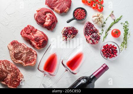 Rohes Set von alternativen Beef Cuts Chuck Augenrolle, obere Klinge, Rumpsteak mit Rotwein in Glas und Flasche, Kräuter und Granatapfel. Bio-Fleisch. Weiß Stockfoto