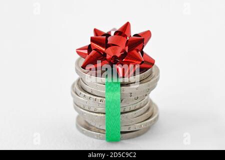 Stapel von Euro-Münzen mit Band und Geschenkschleife verpackt - Konzept der Wirtschaft und Geldgeschenk Stockfoto