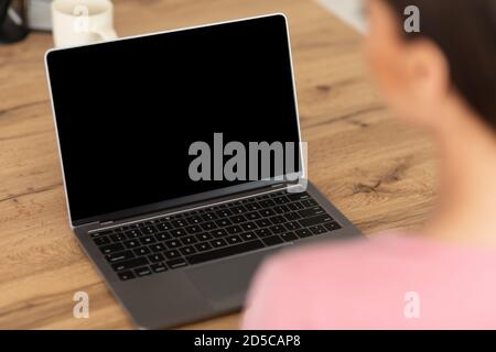Frau arbeitet auf Laptop mit leeren schwarzen Bildschirm für mockup Stockfoto