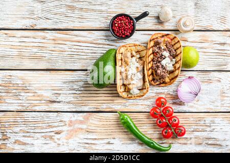 Hausgemachtes Taco mit Huhn und Rindfleisch in der Nähe von rohen Zutaten über weiß strukturierten alten Tisch, Draufsicht mit Platz für Text. Stockfoto