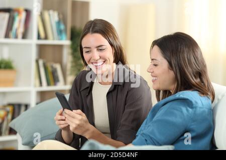 Glückliche Freunde sitzen auf einer Couch zu Hause Überprüfung smart Telefoninhalt Stockfoto