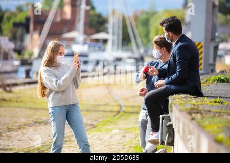 Zwei Männer und eine Frau in Corona-Zeit, mit Alltagsmasken, in der Stadt. Freizeit mit Maske im Freien. Stockfoto