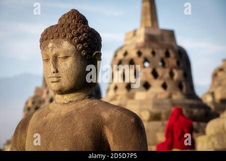 Buddha Statue mit einem buddhistischen Mönch betet im Rücken, Borobudur Tempel Komplex, Borobudur, Yogyakarta, Java, Indonesien Stockfoto