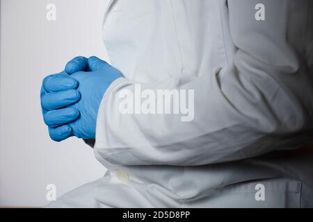 Arzt in blauen OP-Handschuhen mit gekreuzten Händen, Bedenken klinischen Bericht Stockfoto