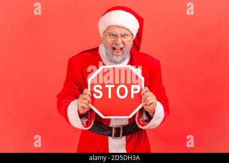 Wütend grauen bärtigen Mann in Brillen und weihnachtsmann Kostüm schreien halten Stoppschild, keine Möglichkeit, Warnung vor Feiertagen Feier. Studio-Sho Stockfoto