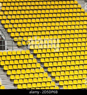 Viele Reihen von gelben Sitzen in einem großen Sportstadion ohne Zuschauer mit Betontreppen. Stockfoto