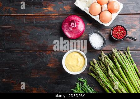 Rohe Spargeleier und französische Dressing-Zutaten mit dijon-Senf, Zwiebel-Estragon auf dunklem Holzhintergrund, Draufsicht mit Platz für Text. Stockfoto