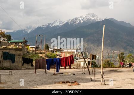 Munsyari, Uttarakhand, Indien - April 2019: Wäscheständer auf der Wäscheleine auf dem Dach eines Gebäudes mit Blick auf schneebedeckte Himalaya-Berge Stockfoto