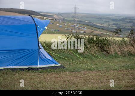 Ein einziges modernes blaues Zelt mit verschiedenen Kulturen und Winkeln In einem Feld mit Kopieplatz, um im Camping zu verwenden Geschichten Stockfoto