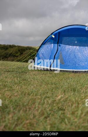 Ein einziges modernes blaues Zelt mit verschiedenen Kulturen und Winkeln In einem Feld mit Kopieplatz, um im Camping zu verwenden Geschichten Stockfoto