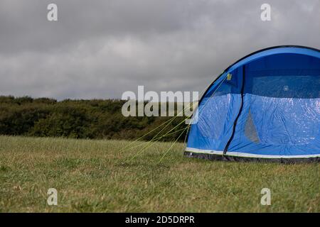 Ein einziges modernes blaues Zelt mit verschiedenen Kulturen und Winkeln In einem Feld mit Kopieplatz, um im Camping zu verwenden Geschichten Stockfoto