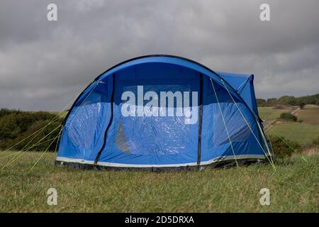 Ein einziges modernes blaues Zelt mit verschiedenen Kulturen und Winkeln In einem Feld mit Kopieplatz, um im Camping zu verwenden Geschichten Stockfoto