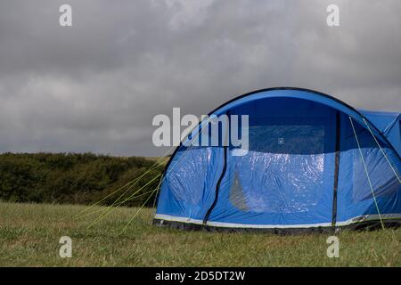 Ein einziges modernes blaues Zelt mit verschiedenen Kulturen und Winkeln In einem Feld mit Kopieplatz, um im Camping zu verwenden Geschichten Stockfoto